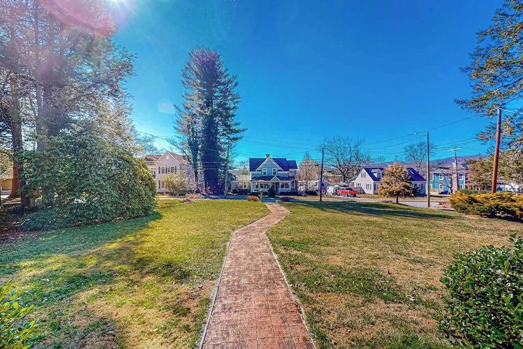 A residential street with a paved walkway, houses, and trees.