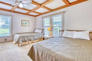 Ein Schlafzimmer mit zwei Betten, einem Deckenventilator, einem Fenster mit Jalousien und einem gerahmten Bild an der Wand.