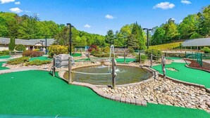 Un parcours de minigolf avec un étang, une pelouse artificielle verte et des aménagements paysagers environnants.