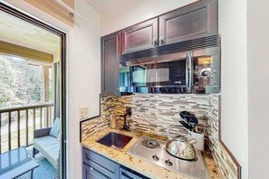 A kitchen with a built-in microwave, a sink, and a stove.