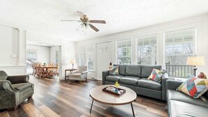 A spacious living room with a dark leather sofa, a round coffee table, and a dining area with wooden chairs. - Junaluska Lodge (Lake Junaluska)