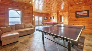 A wooden interior with a ping pong table, a sofa, and a billiards table. - Rustic mountain-view home with deck, fire pit, hot tub, fireplace, & game room (Lake Lure)