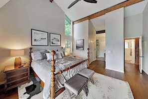 A bedroom with a large bed, a wooden headboard, a nightstand, a bench, and framed pictures on the wall. - Mountain gem w/pool,golf, hot tub, tennis, beach, wellness center - dog-friendly (Lake Lure)