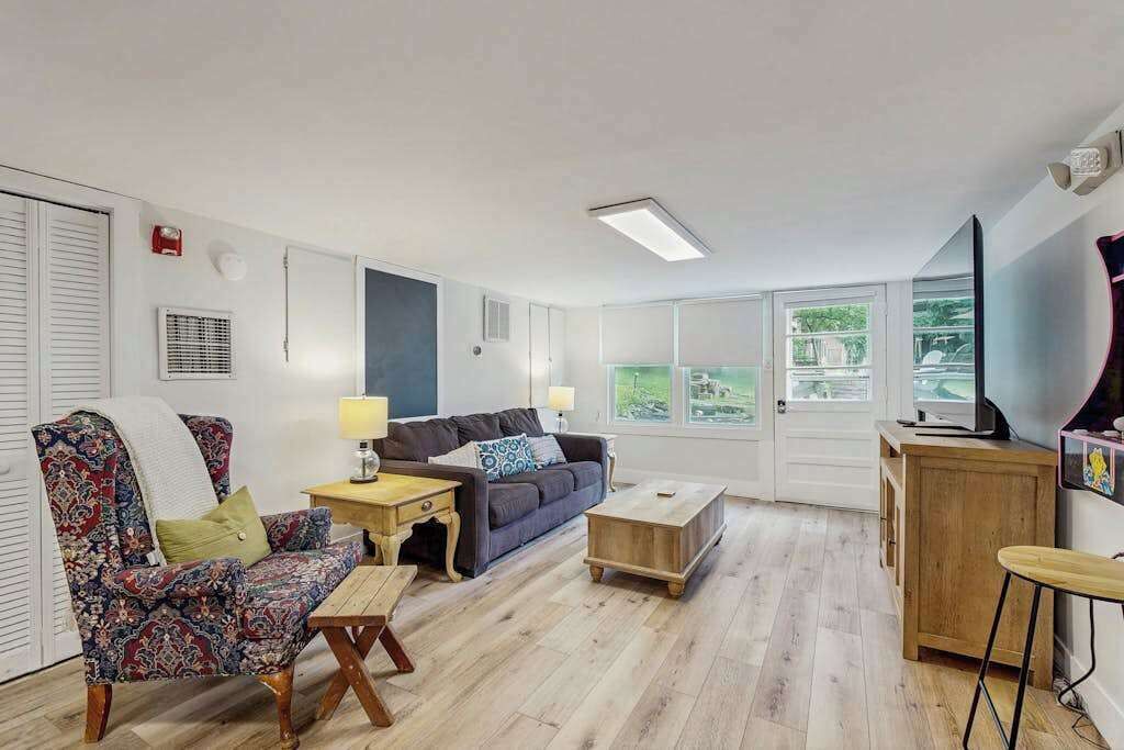 A living room with a sofa, armchair, coffee table, and a TV on a wooden cabinet.