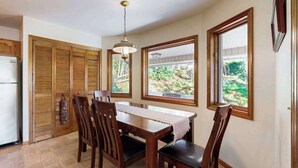 Un espace repas comprenant une table et des chaises, un luminaire suspendu et une vue par la fenêtre.