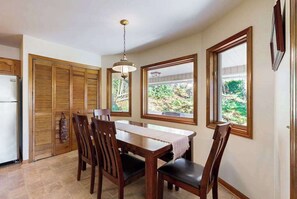 A dining area with a table and chairs, a hanging light fixture, and a view through a window. - Junaluska Gem (Lake Junaluska)