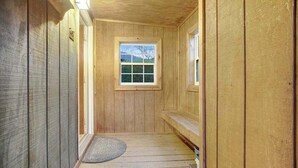 Un pasillo interior de madera con una ventana, una puerta y una alfombra pequeña en el suelo.