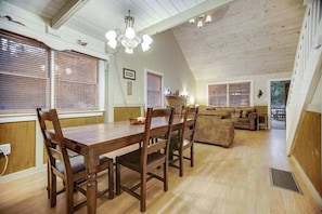 A dining area with a wooden table and chairs, a sofa, and a chandelier.
