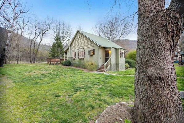 A single-story house with a green roof, a front porch, and a small front yard.
