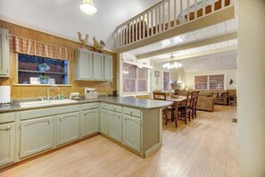 A spacious kitchen with a large island, wooden cabinets, and a dining area with a table and chairs.