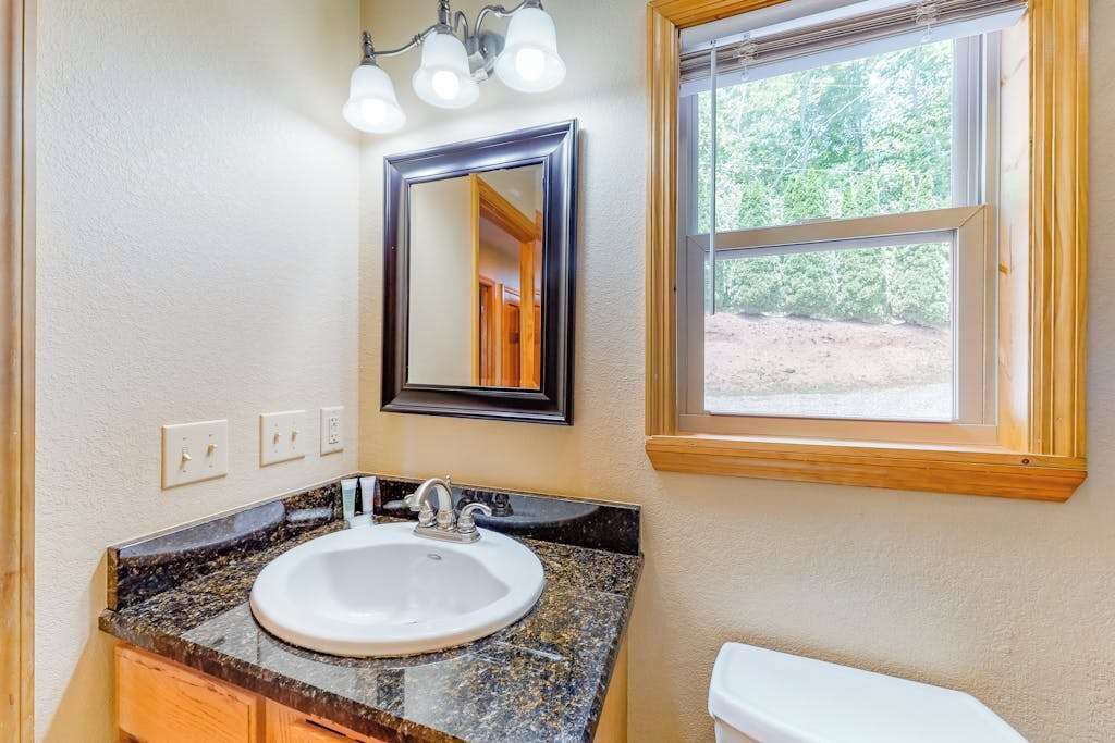 A bathroom with a sink, mirror, and window.
