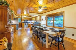 A wooden interior with a dining area, kitchen, and large windows. - Lazy Bear Lookout (Franklin)