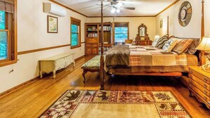 Un dormitorio con cama, ventilador de techo, estantería, cómoda y ventana.