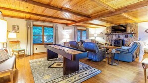 Una sala de estar acogedora con mesa de fútbol, asientos cómodos, chimenea y ventanas amplias.