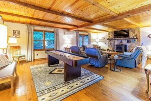 A cozy living room with a foosball table, comfortable seating, a fireplace, and large windows. - Lazy Bear Lookout (Franklin)