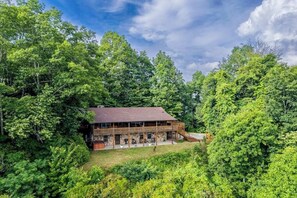A large lodge with a prominent wooden structure, multiple decks, and a stone foundation, surrounded by dense forest. - Lazy Bear Lookout (Franklin)