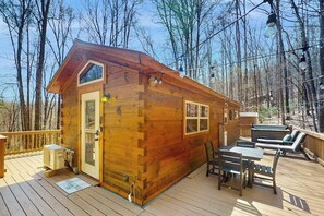 Eine Holz-Blockhütte mit einer Terrasse, einem Tisch, Stühlen und einem Whirlpool.
