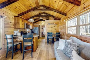 Ein Holzblockhaus-Interieur mit Küche, Essbereich und einer Couch mit Kissen.