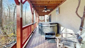 Eine Holzterrasse mit Whirlpool, Deckenventilator und einem rustikalen Stuhl.