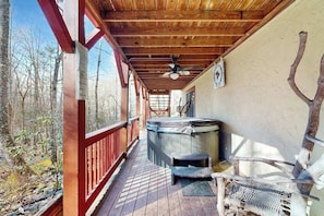 Eine Holzterrasse mit Whirlpool, Deckenventilator und einem rustikalen Stuhl.