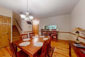 Ein Esszimmer mit Holztisch, Stühlen, einer Pendelleuchte und einer Treppe.