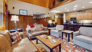 A spacious living area with leather sofas, a coffee table, and a kitchen in the background. - Tuckaway Retreat (Sylva)