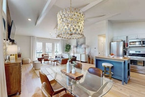 A modern kitchen with a central island, a dining area with a glass table, and a living space with a sofa and chairs. - Cashmere Cottage (Cashiers)