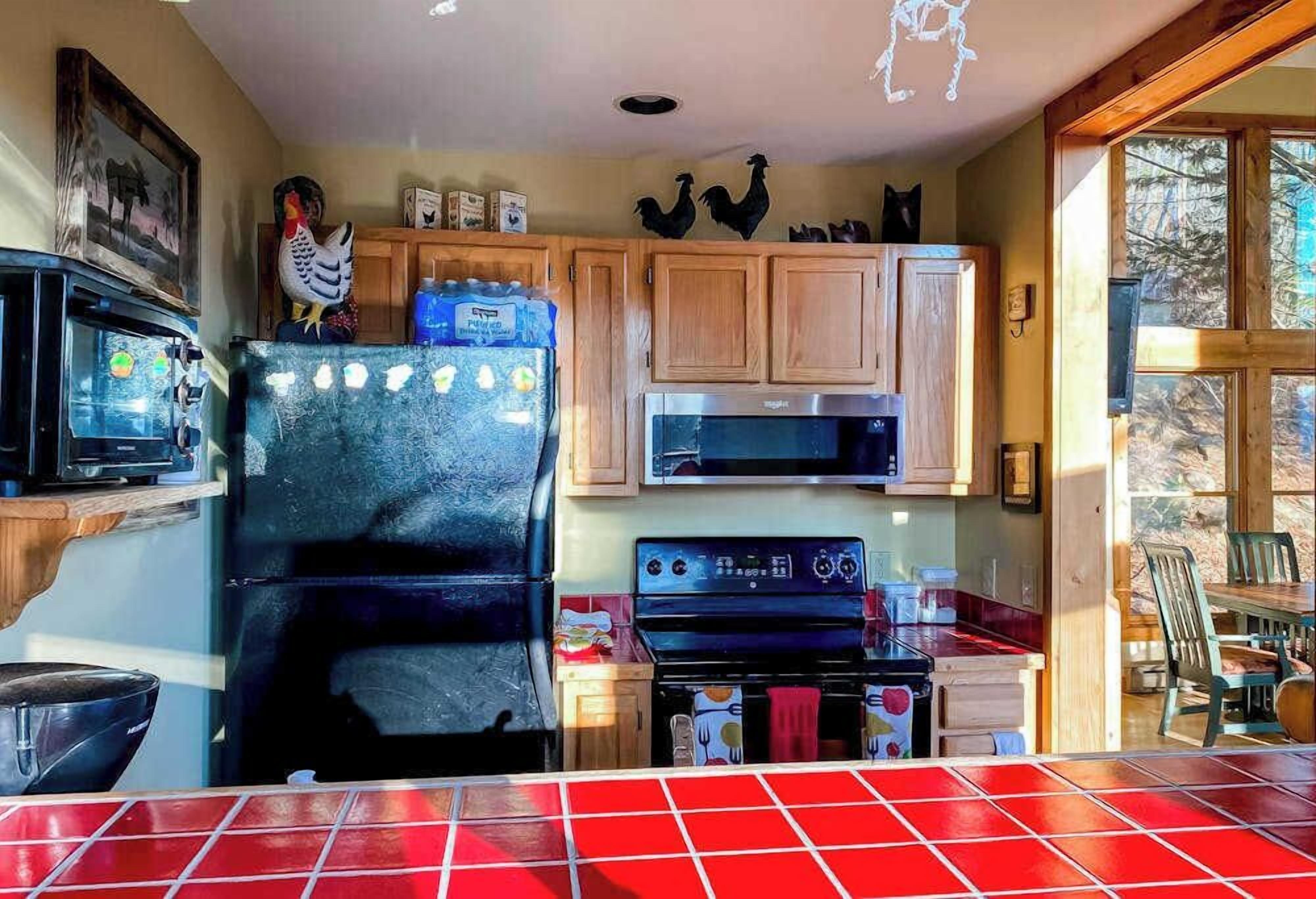 A kitchen with wooden cabinets, a refrigerator, a microwave, and a stove.