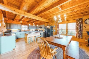A wooden cabin interior with a kitchen, dining area, and a large window. - Secluded cabin with mountain views, fire pit & billiards (Sylva)