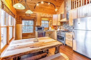 Ein Holzblockhaus-Interieur mit Küche, Esstisch und großen Fenstern.