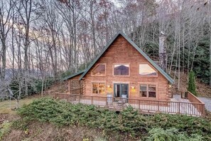 Eine Holzhütte mit Veranda, großen Fenstern und Schornstein.