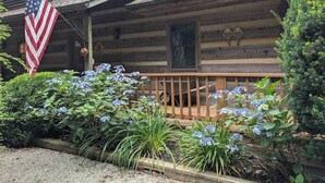 A wooden cabin with a porch, an American flag, and a welcome sign. - Rocky Knob Getaway (Scaly Mountain)