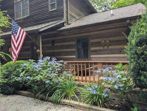 A wooden cabin with a porch, an American flag, and a welcome sign. - Rocky Knob Getaway (Scaly Mountain)