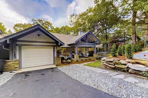 A two-story house with a garage, stone foundation, and a landscaped front yard. - Stephen Cottage (Highlands)