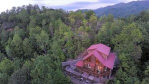Una baita dal tetto rosso, immersa in una fitta foresta, con vista su montagne lontane.