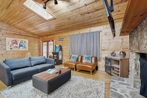 A wooden interior with a sofa, a coffee table, a fireplace, and a television. - Maggie Valley cabin with wrap around porch & gorgeous mountain views (Maggie Valley)