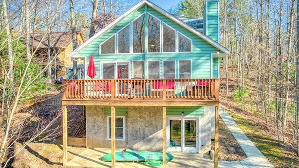 Une maison à deux étages avec un balcon, une cheminée et une terrasse.