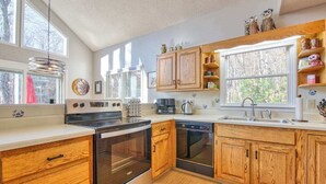 Une cuisine moderne avec des meubles en bois, des appareils électroménagers en acier inoxydable et de grandes fenêtres.