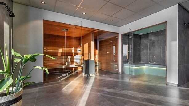 En moderne lobby med reception, et glasafskærmet bruseområde og en potteplante.
