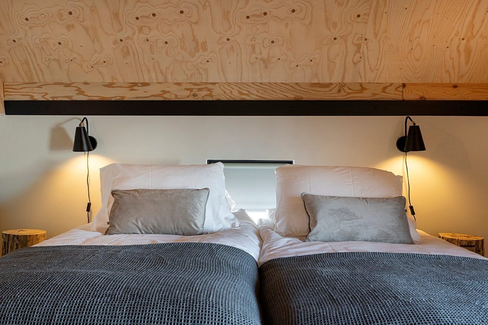 A double bed with two pillows, a headboard, and two bedside lamps.