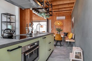 Eine moderne Küche mit Einbauofen, einer Kaffeemaschine und einem Essbereich mit Holztisch und Stühlen.