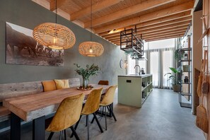 Eine moderne Küche mit Kochinsel, Pendelleuchten und einem Essbereich mit Holztisch und Stühlen.