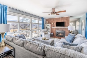 A living room with a sofa, ottoman, and a fireplace. - The Willows (Waynesville)