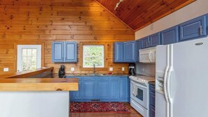 Una cocina con paredes de madera, armarios azules, un refrigerador blanco y una encimera de madera.