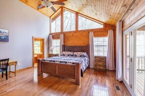 Ein Schlafzimmer mit Holzbalkendecke, einem Bett, einem Fenster und einer Tür.