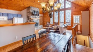 Un interior de madera con una mesa de comedor, sillas, chimenea y una pared de piedra.