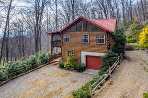 Eine Blockhütte mit rotem Dach, einer Garage und einem Balkon.