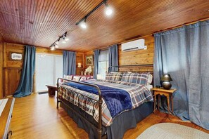 Ein Zimmer mit Holzwänden, einem Bett, einem Nachttisch und einem Fenster mit Vorhängen.