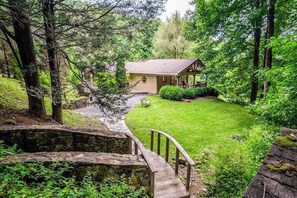 Eine Lodge mit einer Steinbrücke, einer Veranda und einem gepflegten Rasen.
