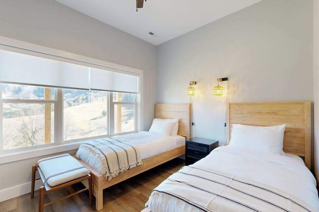 Una camera da letto con due letti, una panca e un'ampia finestra con vista.